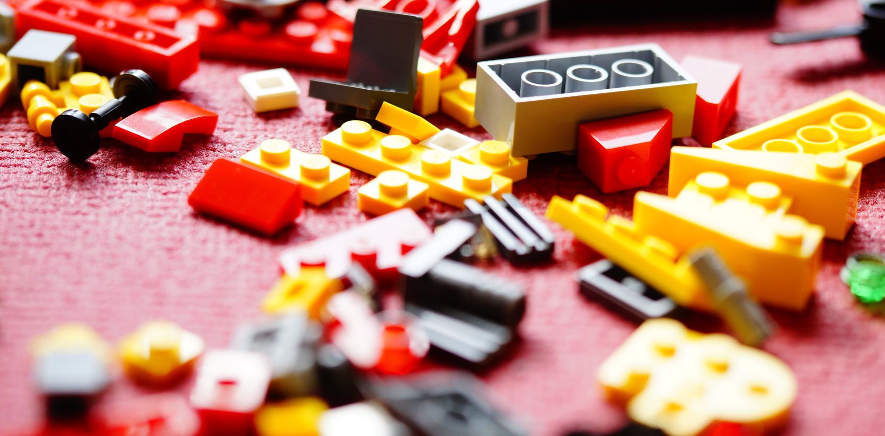 Losse LEGO-steentjes in rood, geel en wit op een tafel